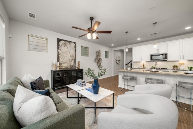 living room with ceiling fan and dark wood-type flooring