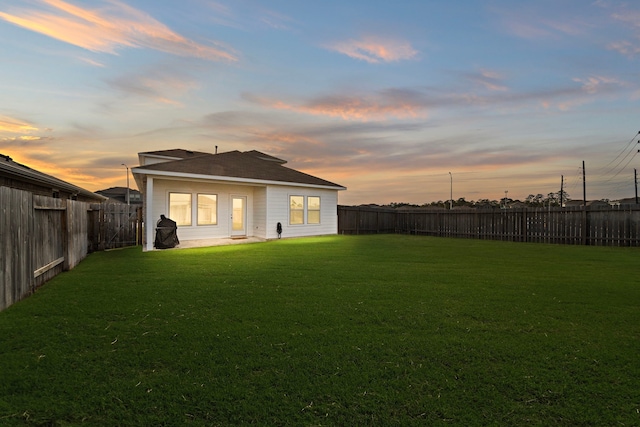 back house at dusk featuring a yard