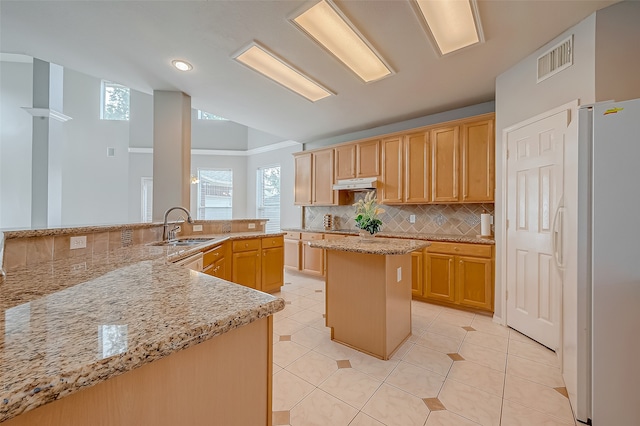 kitchen with kitchen peninsula, backsplash, sink, a center island, and white fridge with ice dispenser