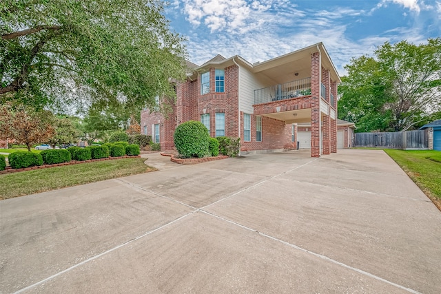 view of front facade with a balcony, a front yard, and a garage