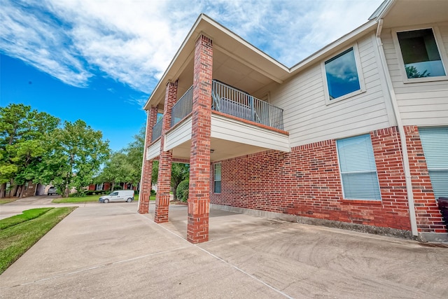 2519 Meadow Tree Ln, Spring, TX 77388 - view of side of home featuring a carport, brick siding, and a balcony