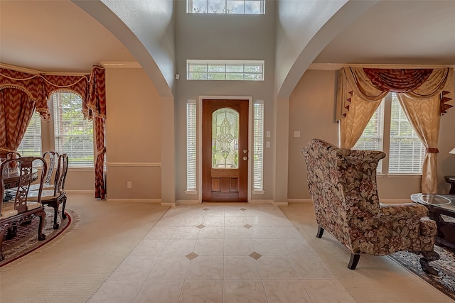 entryway with light tile patterned floors, crown molding, and a wealth of natural light