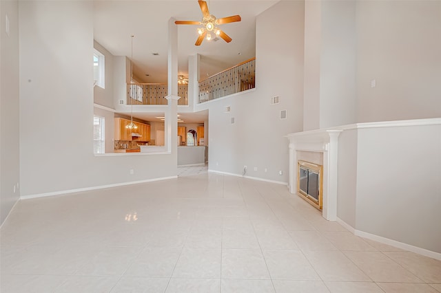 unfurnished living room featuring a high ceiling, light tile patterned floors, and ceiling fan