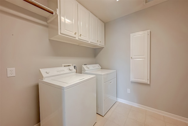 laundry room featuring washing machine and dryer, light tile patterned flooring, and cabinets