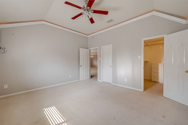 unfurnished bedroom with a closet, a spacious closet, ceiling fan, and lofted ceiling