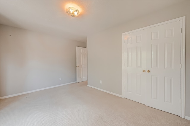 unfurnished bedroom with a closet and light colored carpet