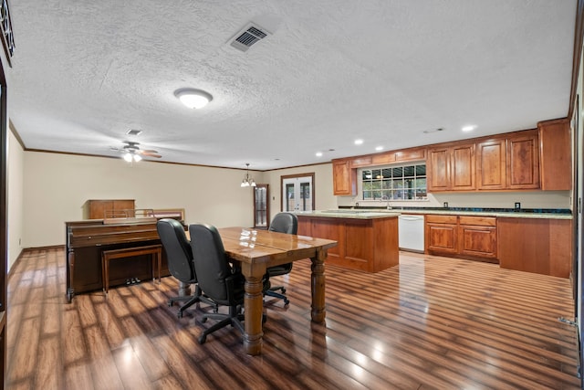 dining area featuring sink, dark wood-type flooring, a textured ceiling, ceiling fan with notable chandelier, and ornamental molding