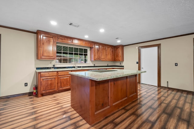 kitchen featuring dark hardwood / wood-style flooring, a center island, light stone counters, and crown molding