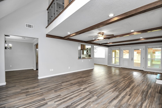 unfurnished living room featuring ceiling fan with notable chandelier, ornamental molding, a textured ceiling, beamed ceiling, and dark hardwood / wood-style flooring