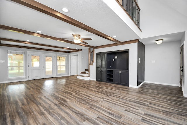 unfurnished living room with french doors, dark hardwood / wood-style floors, ceiling fan, a textured ceiling, and beamed ceiling