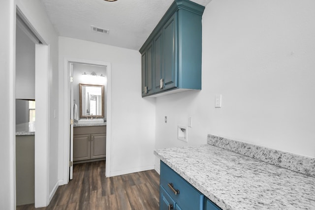 kitchen featuring a textured ceiling, sink, blue cabinets, and dark wood-type flooring