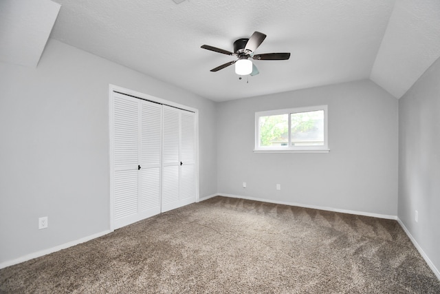 unfurnished bedroom featuring lofted ceiling, ceiling fan, a textured ceiling, carpet floors, and a closet