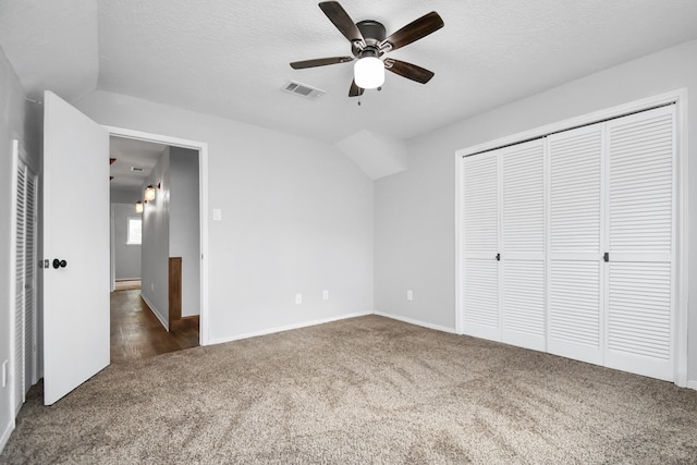 unfurnished bedroom featuring ceiling fan, dark carpet, and a textured ceiling