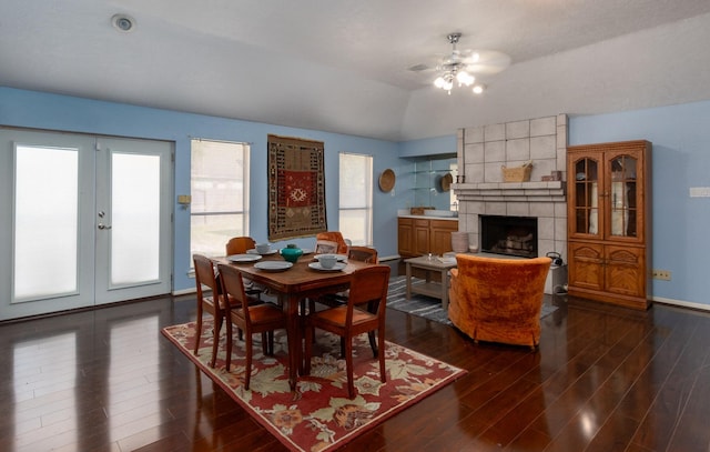 dining area featuring ceiling fan, lofted ceiling, dark wood-type flooring, and a tile fireplace