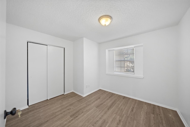 unfurnished bedroom featuring a textured ceiling, light hardwood / wood-style floors, and a closet