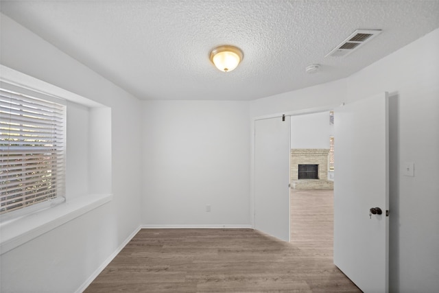 spare room featuring light hardwood / wood-style floors and a textured ceiling