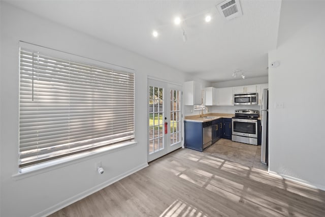 kitchen featuring appliances with stainless steel finishes, french doors, sink, white cabinets, and light hardwood / wood-style floors