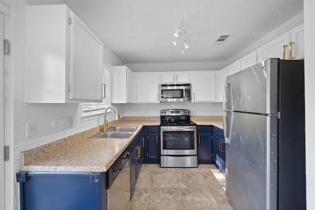 kitchen with a textured ceiling, stainless steel appliances, blue cabinets, sink, and white cabinets