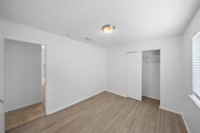 unfurnished bedroom featuring a textured ceiling, light hardwood / wood-style flooring, and a closet