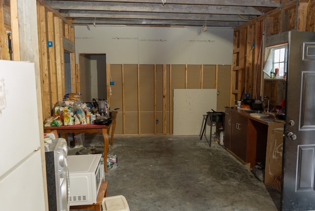 basement featuring white refrigerator and sink