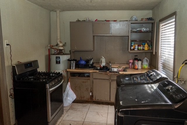 kitchen featuring a textured ceiling, gas stove, washing machine and dryer, and sink