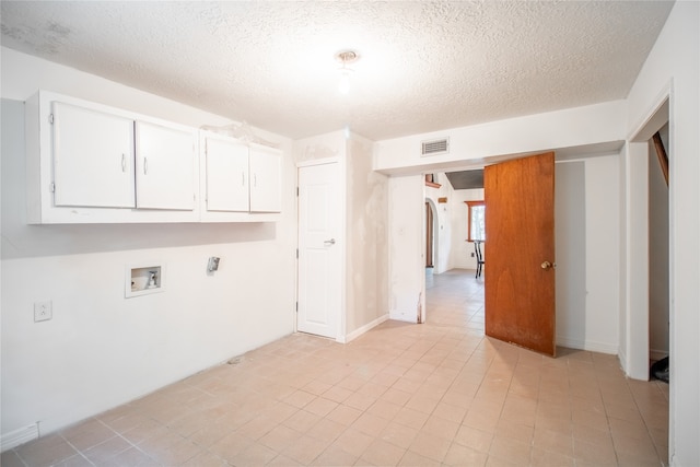 laundry area featuring cabinets, hookup for a washing machine, a textured ceiling, and light tile patterned floors