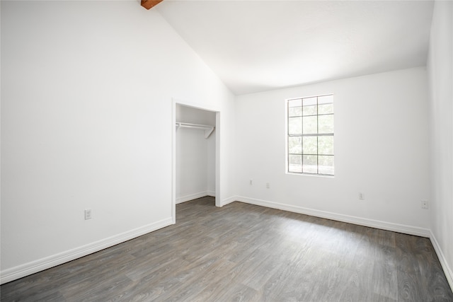 unfurnished bedroom featuring hardwood / wood-style floors, vaulted ceiling, and a closet