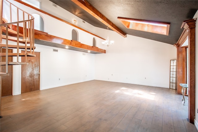 unfurnished room with high vaulted ceiling, wood-type flooring, a textured ceiling, and an inviting chandelier