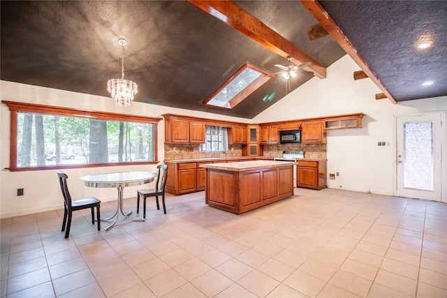 kitchen with ceiling fan with notable chandelier, light tile patterned floors, beamed ceiling, decorative light fixtures, and a kitchen island