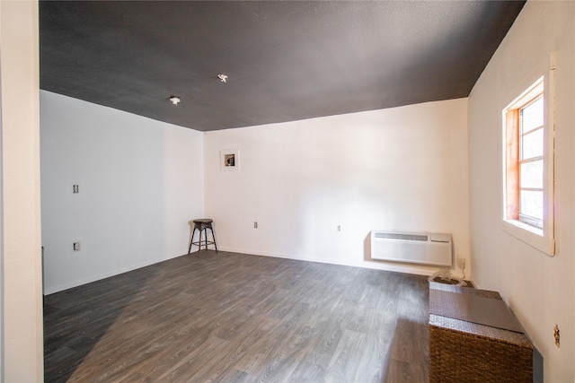 unfurnished room featuring dark hardwood / wood-style flooring and a wall unit AC