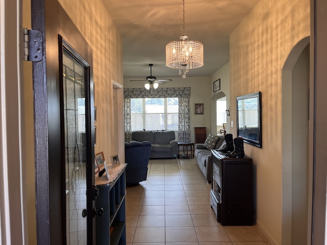 tiled living room featuring ceiling fan with notable chandelier