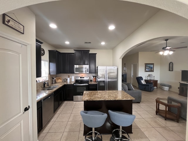 kitchen with lofted ceiling, a breakfast bar area, light tile patterned floors, a kitchen island, and stainless steel appliances