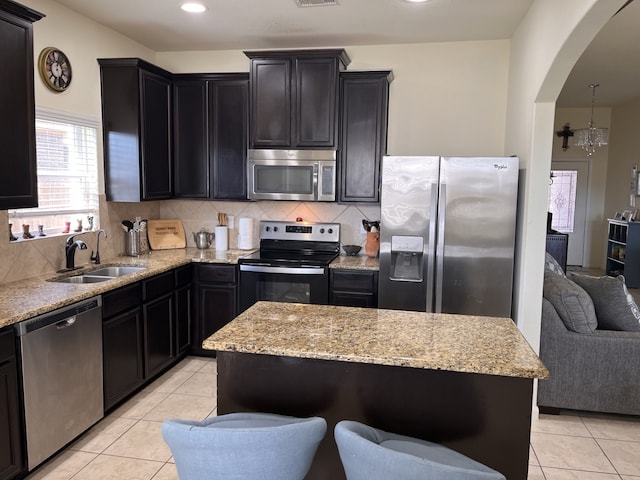 kitchen with a center island, sink, stainless steel appliances, and an inviting chandelier