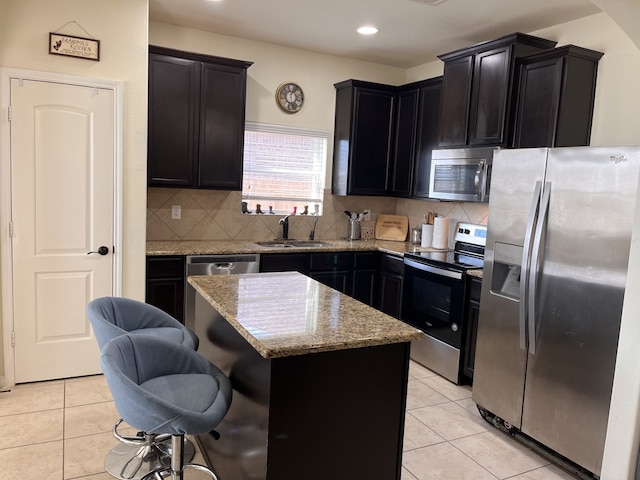 kitchen featuring a breakfast bar, stainless steel appliances, sink, light tile patterned floors, and a kitchen island