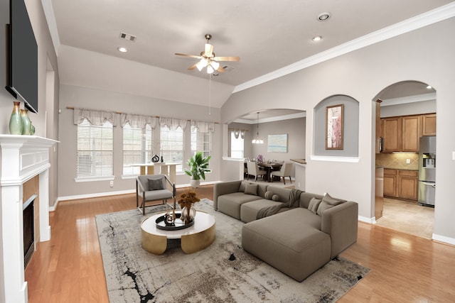 living room with ornamental molding, ceiling fan with notable chandelier, light hardwood / wood-style flooring, and lofted ceiling