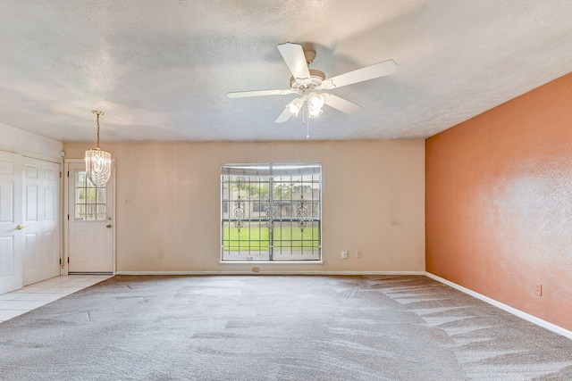 carpeted empty room with ceiling fan with notable chandelier and a textured ceiling