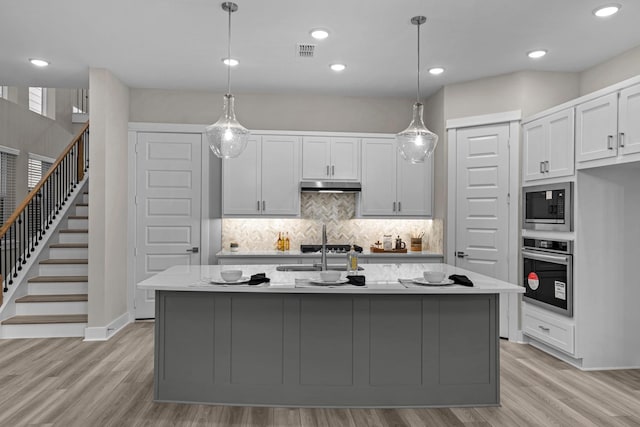 16034 Mason Run Dr, Houston, TX 77079 - kitchen with oven, built in microwave, under cabinet range hood, decorative backsplash, and light wood finished floors