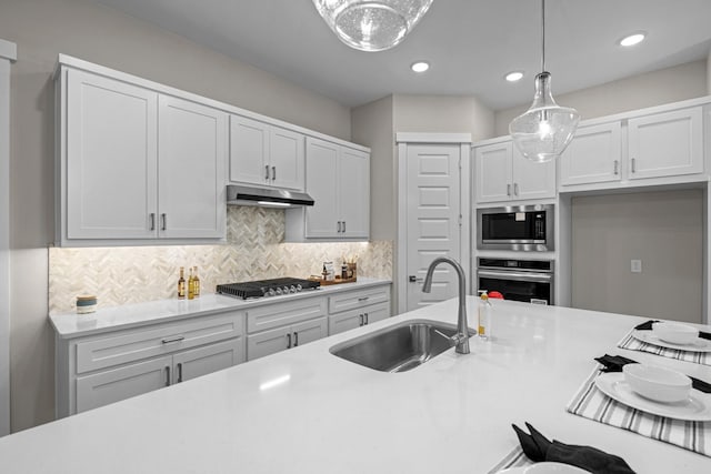 16034 Mason Run Dr, Houston, TX 77079 - kitchen featuring appliances with stainless steel finishes, under cabinet range hood, light countertops, hanging light fixtures, and white cabinetry