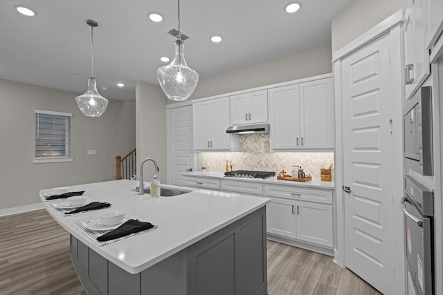 16034 Mason Run Dr, Houston, TX 77079 - kitchen featuring appliances with stainless steel finishes, under cabinet range hood, backsplash, light countertops, and white cabinetry