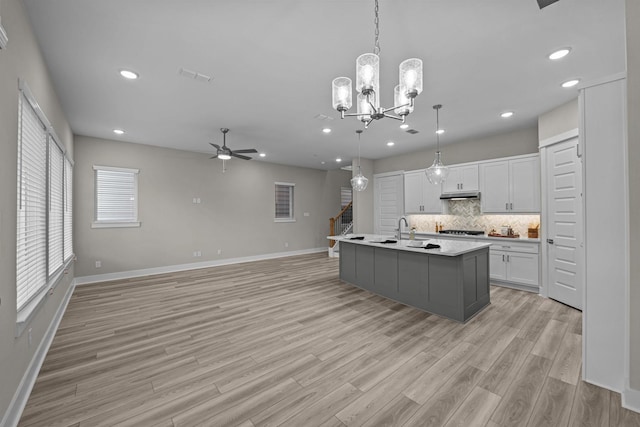 16034 Mason Run Dr, Houston, TX 77079 - kitchen with ceiling fan, backsplash, gas cooktop, white cabinets, and light wood-type flooring