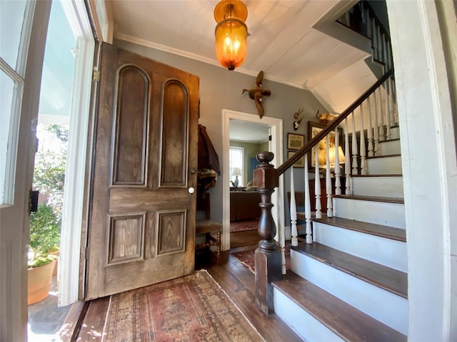 foyer with ornamental molding, lofted ceiling, and dark wood-type flooring