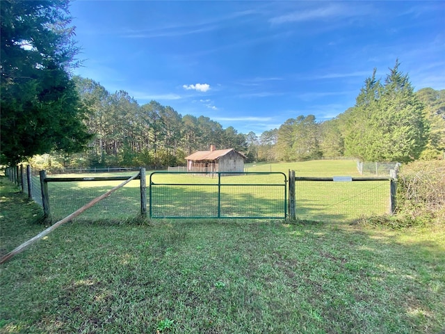 view of gate with a rural view and a yard