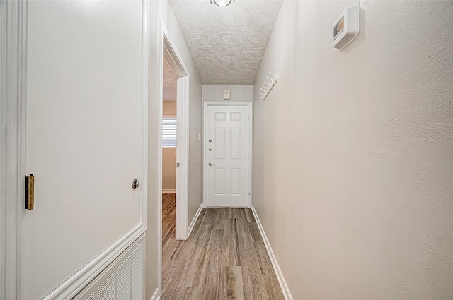 corridor featuring a textured ceiling and light hardwood / wood-style flooring