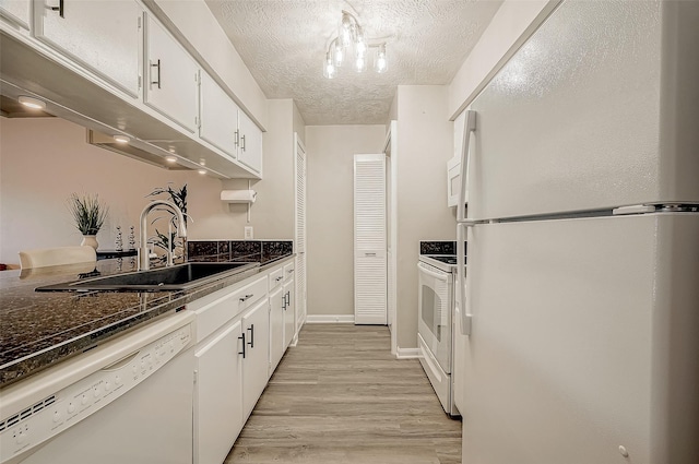 kitchen featuring white appliances, dark stone counters, a textured ceiling, and white cabinets