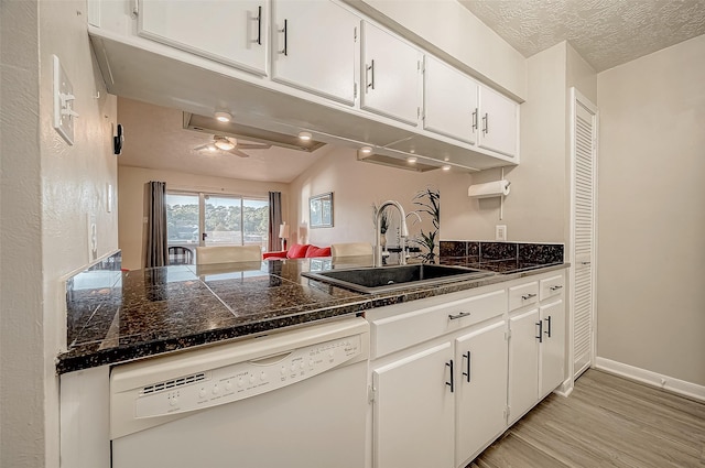 kitchen featuring sink, white cabinets, white dishwasher, a textured ceiling, and light hardwood / wood-style flooring