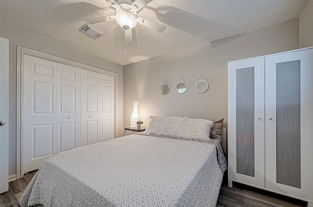 bedroom with dark wood-type flooring, ceiling fan, a closet, and a textured ceiling