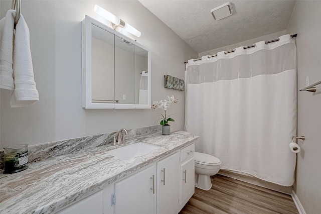 bathroom featuring wood-type flooring, vanity, walk in shower, toilet, and a textured ceiling