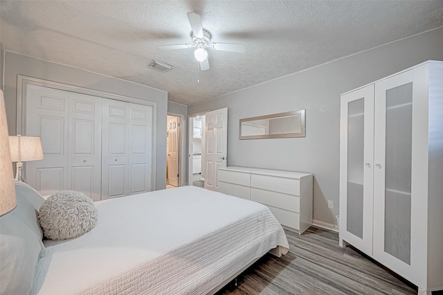 bedroom with a textured ceiling, ceiling fan, and hardwood / wood-style flooring