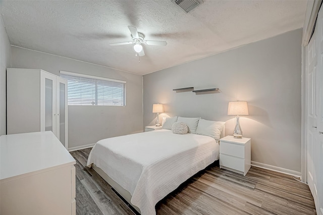 bedroom with ceiling fan, wood-type flooring, a closet, and a textured ceiling