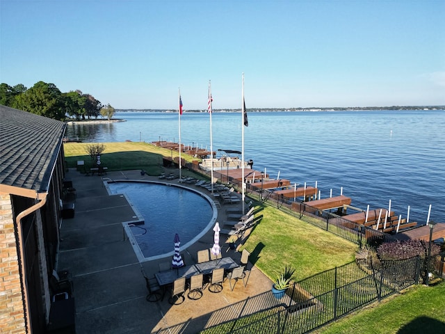 exterior space with a fenced in pool, a patio area, a lawn, and a water view